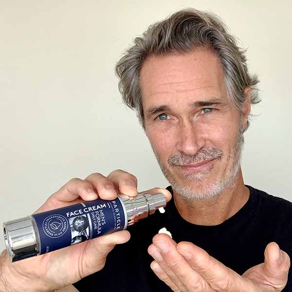 Middle-aged man applying Particle face cream from a pump bottle.