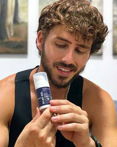 A man holding a Particle Men’s Formula Scar Gel bottle in his hands.