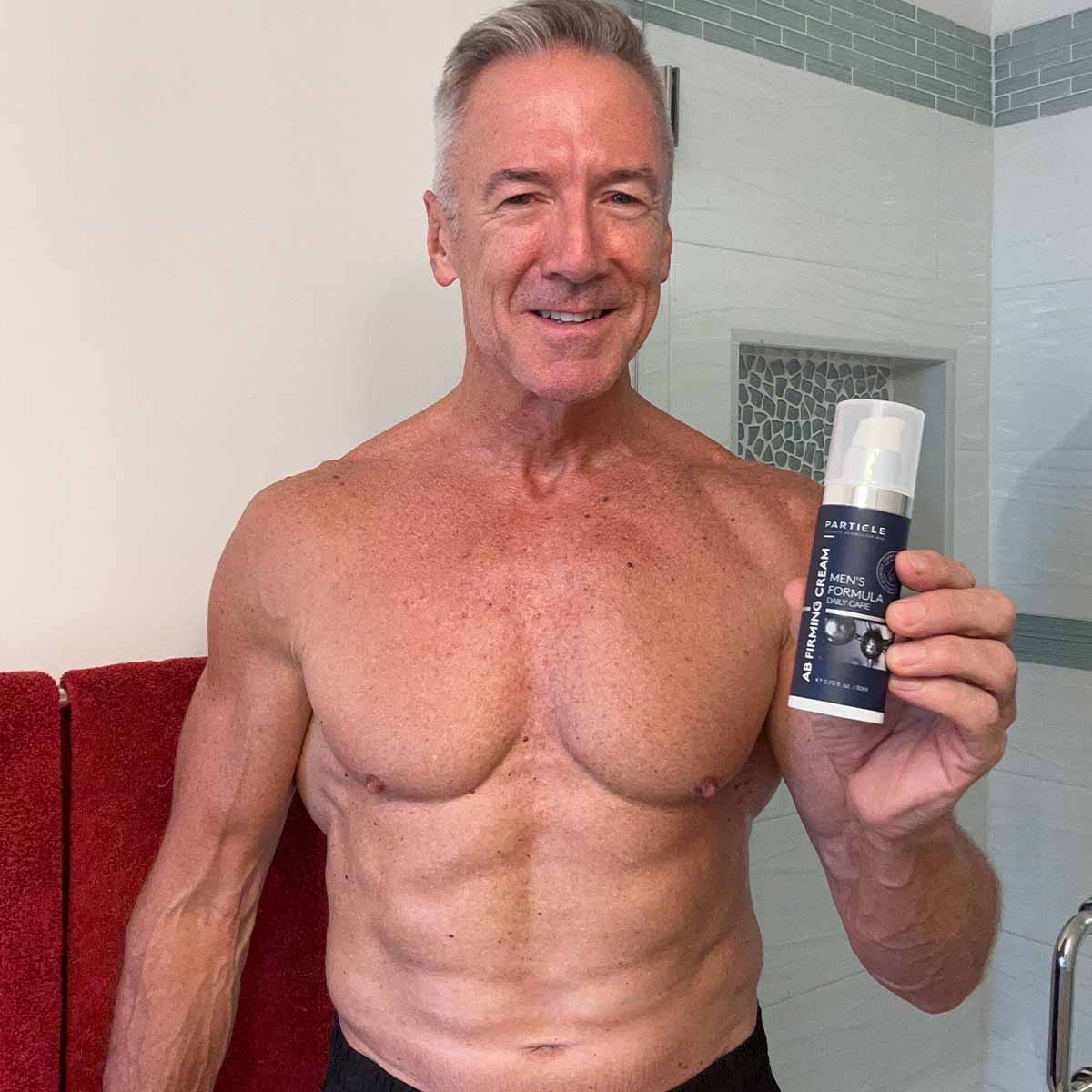 Muscular man holding a bottle Particle AB Firming Cream.