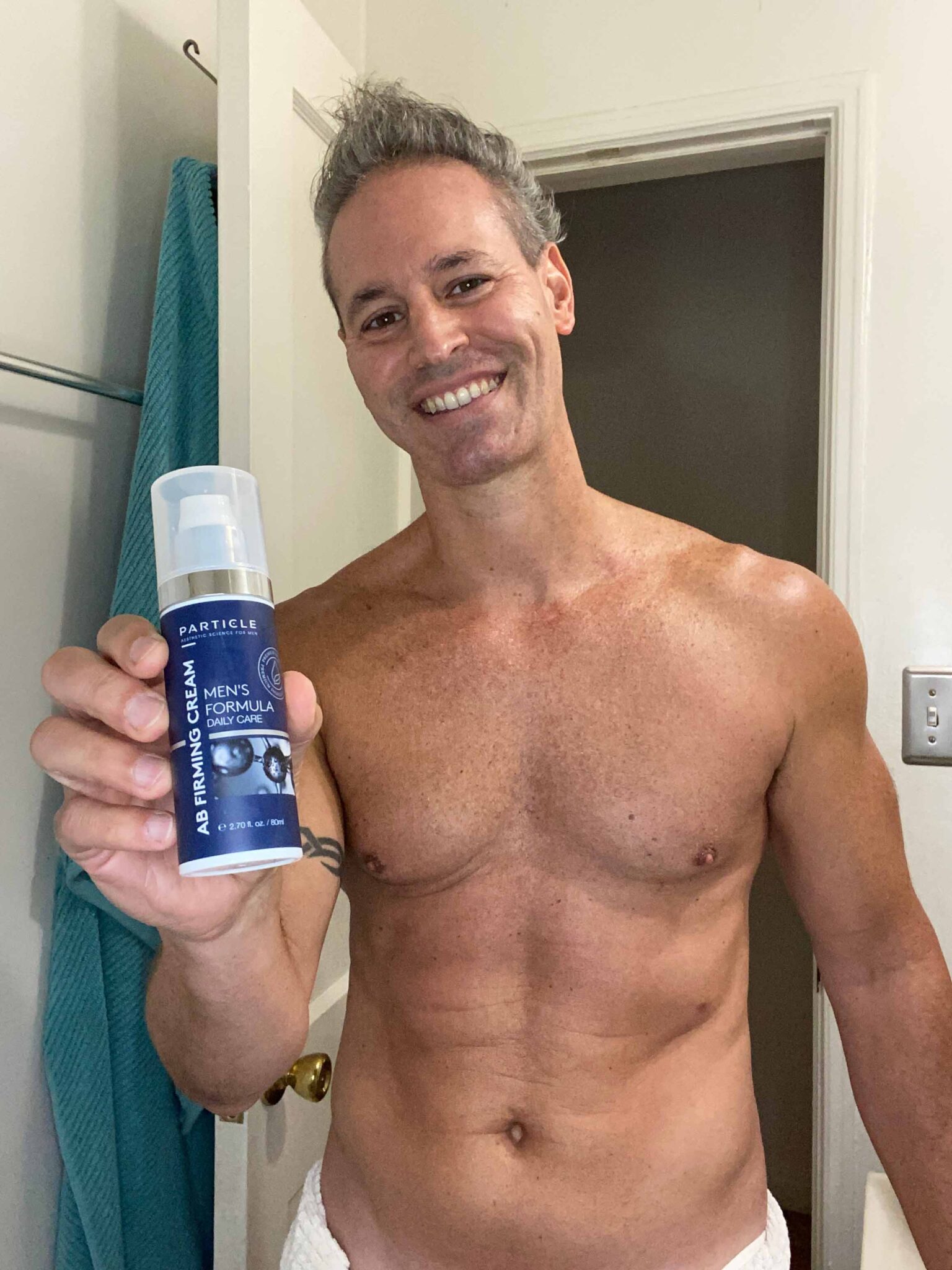 A man holding a bottle of Particle AB Firming Cream Men's Formula Daily Care.