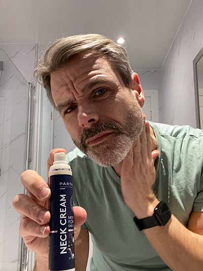 A man applies Particle Neck cream in a bathroom.