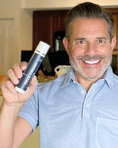 Smiling man shows Particle Daily Care Neck Cream.