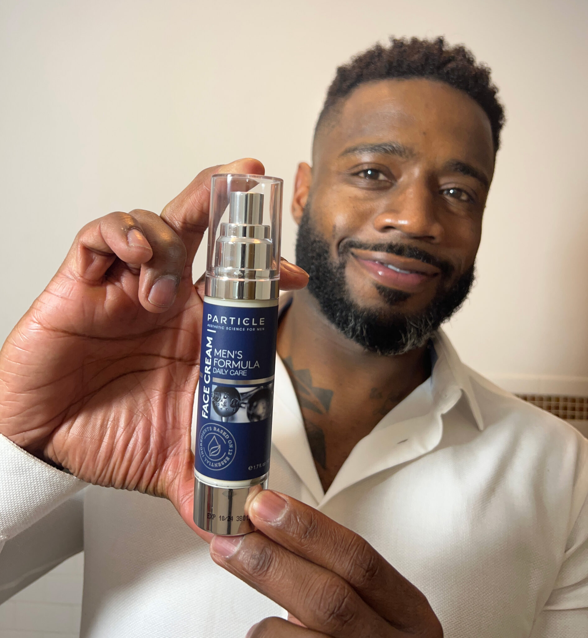 A man holds a bottle of Particle Daily Care Face Cream, aesthetic science for men.