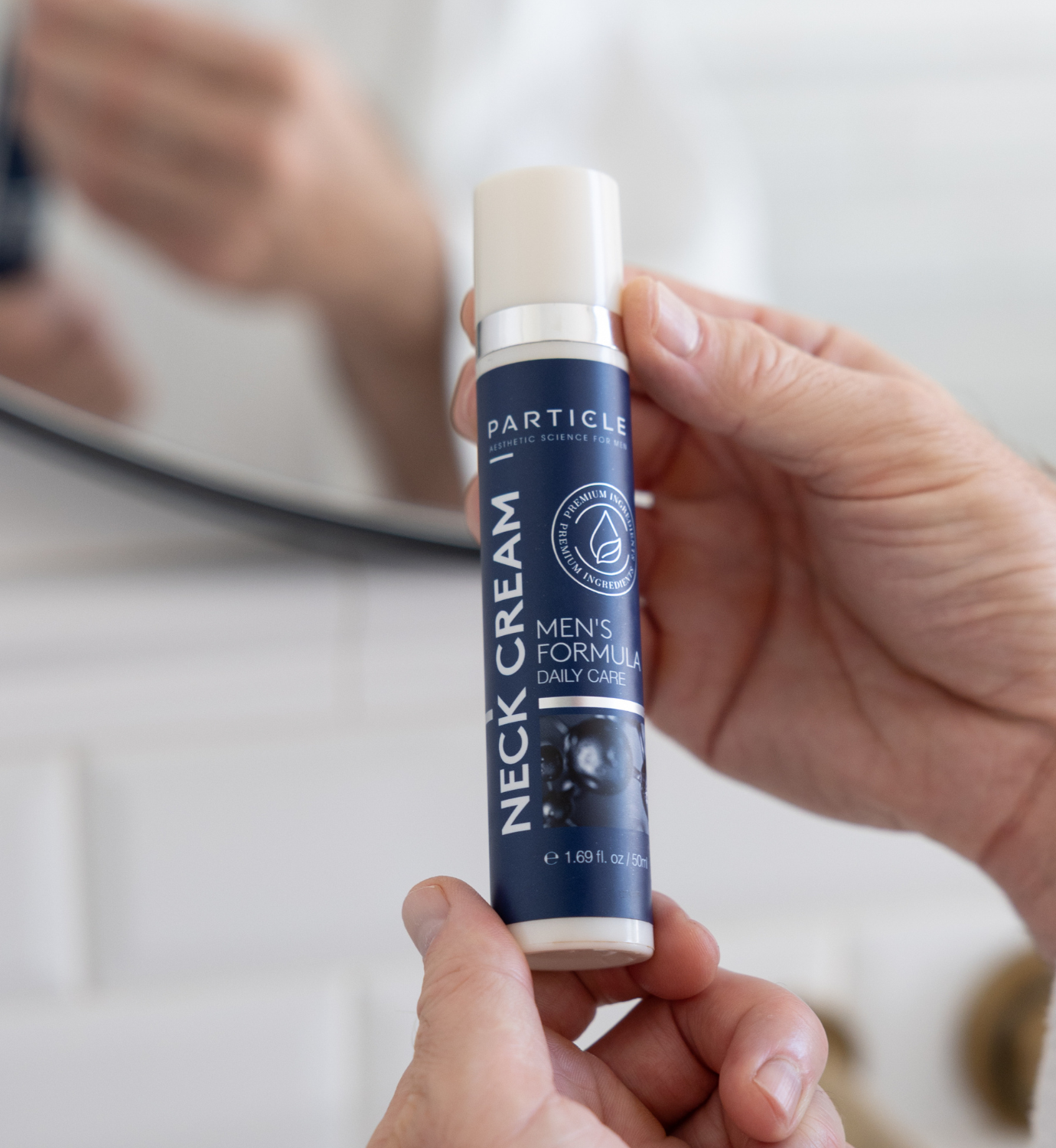 Man holding Particle men’s neck cream bottle during daily skincare routine