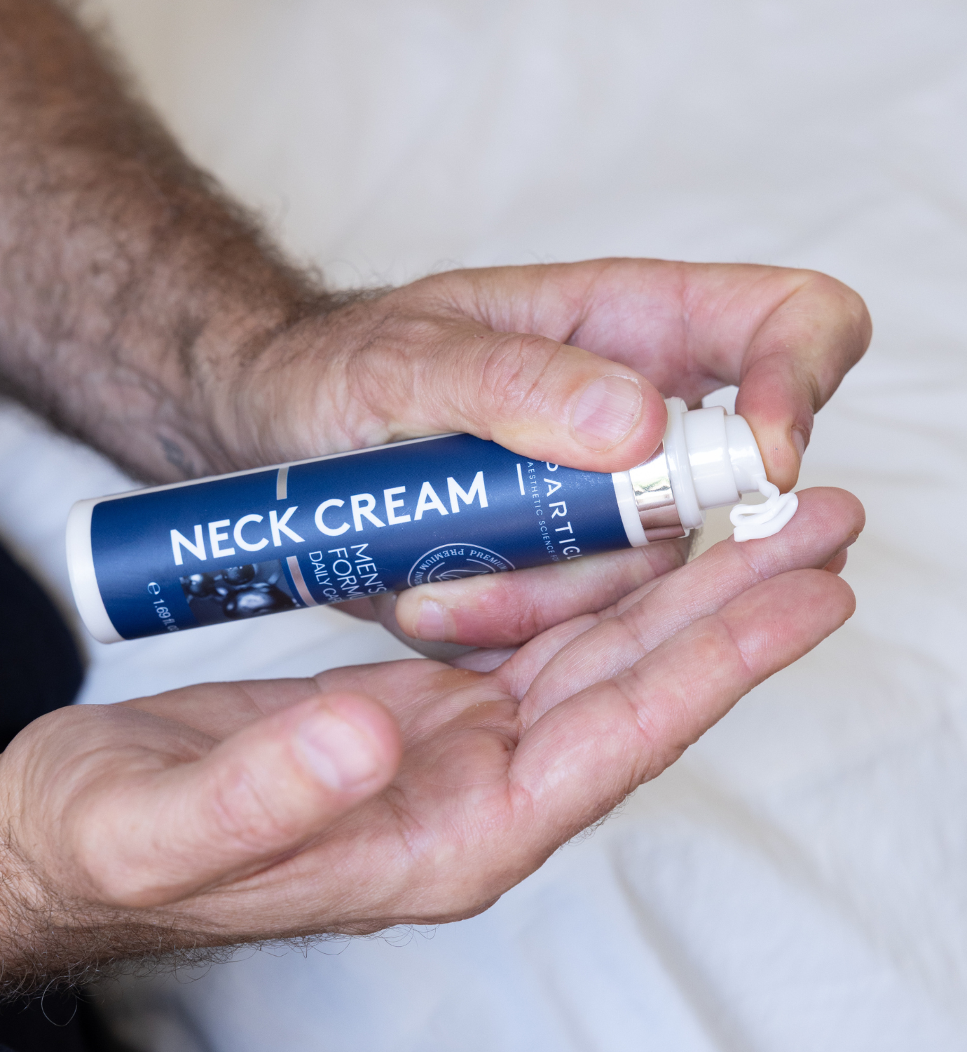Men’s neck cream being dispensed from applicator onto hand