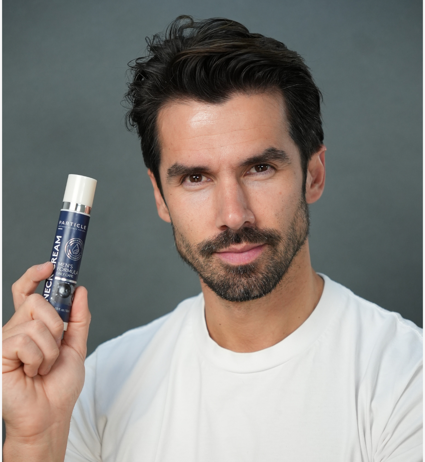 Man holding Particle men’s neck cream bottle, showcasing a modern men’s skincare product