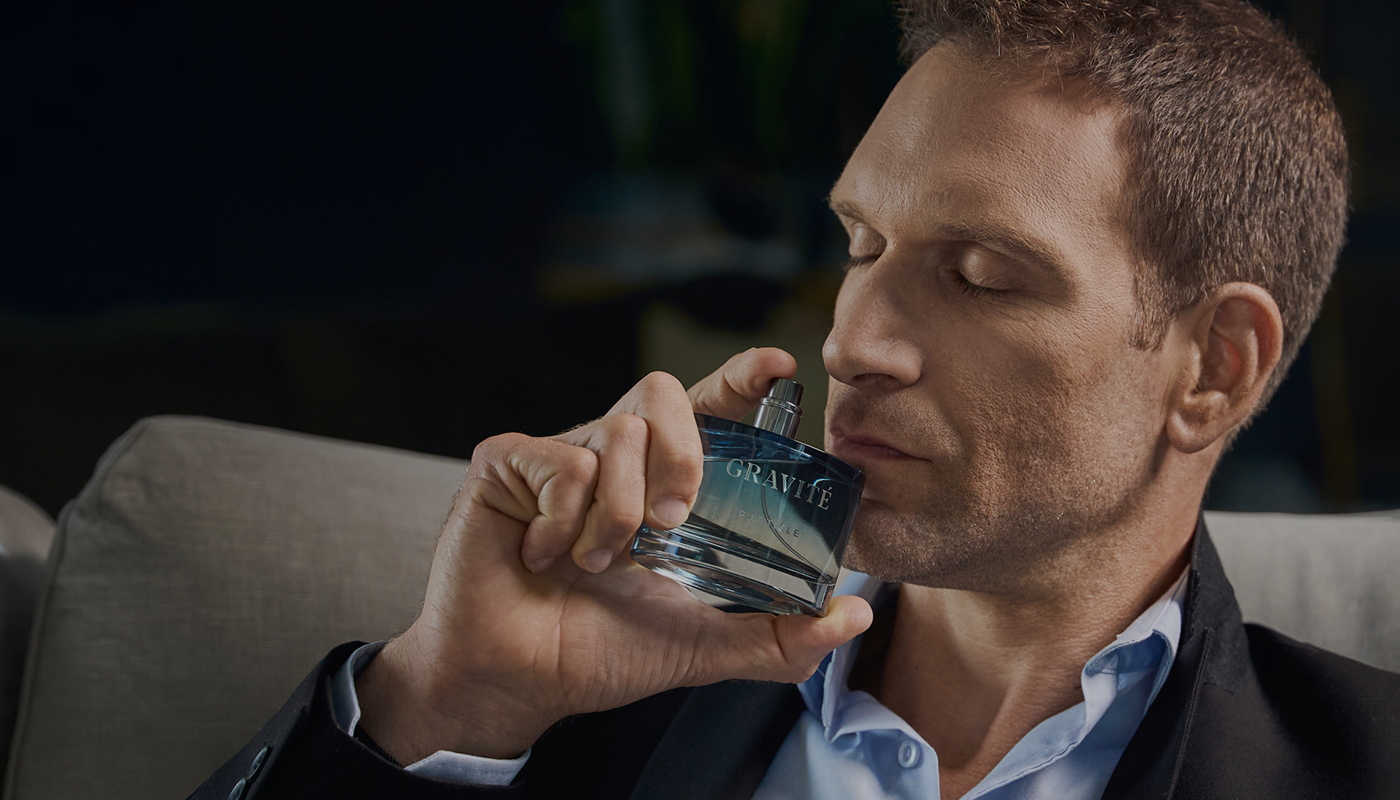 Man smelling Gravité men’s perfume bottle, showcasing a refined masculine fragrance in a close-up lifestyle shot