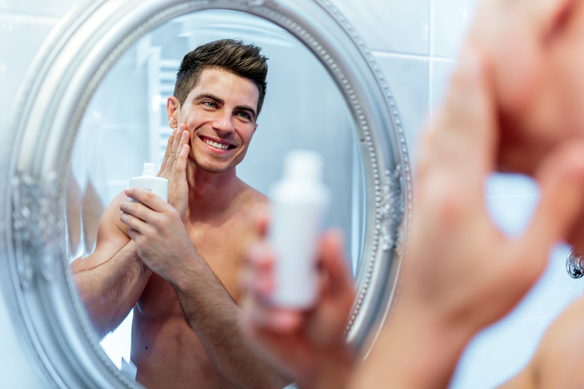 Healthy positive male treating skin with lotion